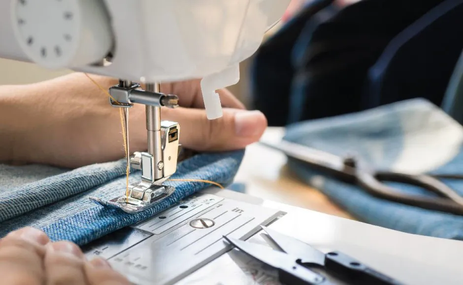 Sastre profesional cosiendo un pantalón de mezclilla a mano